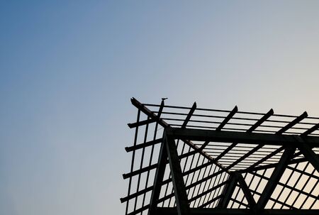 silhouette corner steel structure roof house building. unfinish home project construction site. copy space with blue skyの写真素材