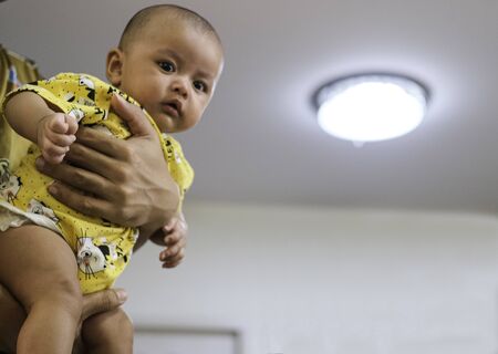 portrait of a cute newborn baby in father holding hand in white wall house with copy space