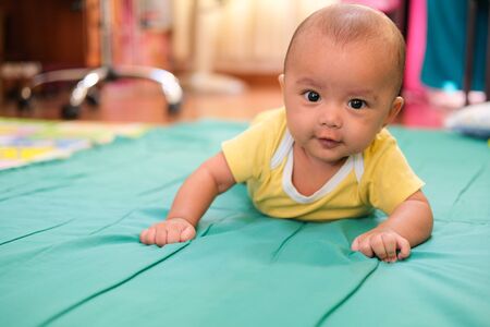 smiling baby happy and training crawling on soft green quilt. learning boy playing toy.