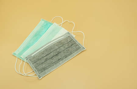 three charcoal green and white paper mask surgical filter dust pollution and disease virus. safety medical equipment. Isolated on yellow background.の写真素材