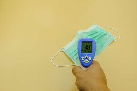 thermometer and green mask surgical filter dust pollution and disease  . safety medical equipment. Isolated on yellow background.の写真素材