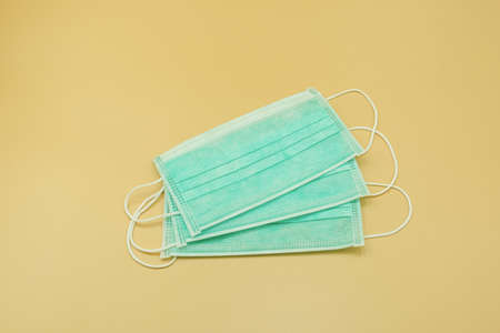 group three green paper mask surgical filter dust pollution and disease virus. safety medical equipment. Isolated on yellow background.の写真素材
