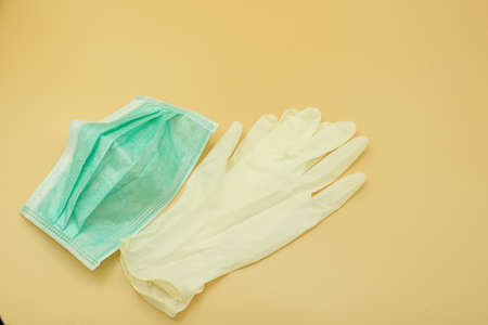 single green paper mask surgical on latex glove protect and filter dust pollution and disease virus. safety medical equipment. Isolated on yellow background.の写真素材