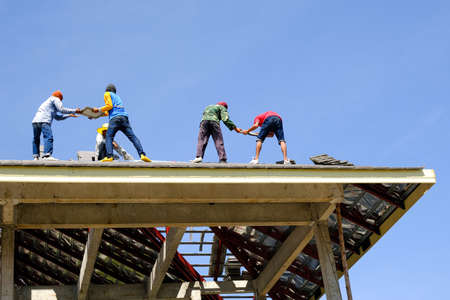 group of male team worker service install roof tiles second floor high building dangerous place.danger job house projectのeditorial素材