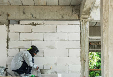 worker use trowel with liquid cement making coner beads in house site building