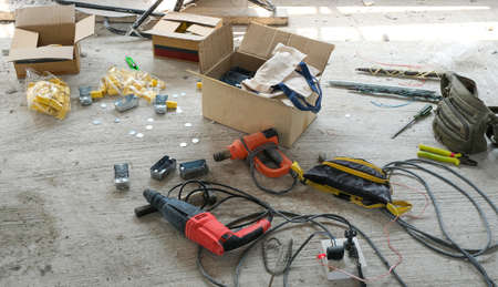 electrician work tools put on the concrete floor. electric drill and spring set tube. block light...