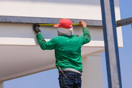 builder worker man working set iron heavy metal prepare for install garage roof . Many aluminium stairs use for workの写真素材
