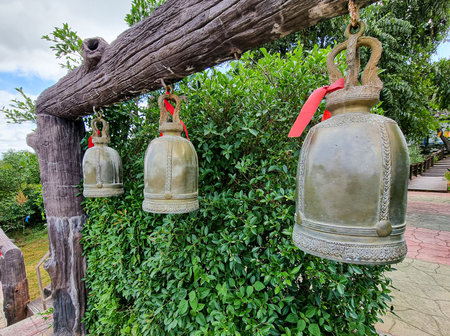 group of ancient lucky gold  bell ring hanging on woonden pole. Thailand buddism tradition temple...