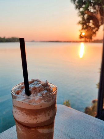 smooties coffee  cool drinking water on the table wood sea and orange sunset down on water backgroundの写真素材