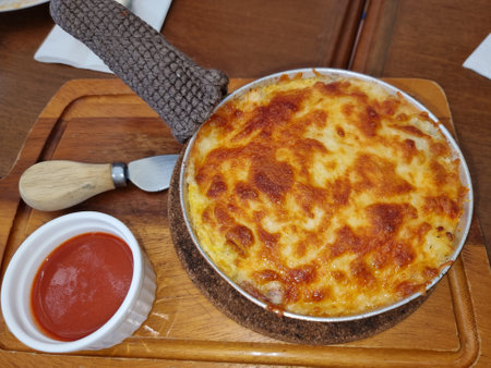 lasagna hot grill in circle pan on wooden plate serve with tomato sauce. homemade pastry cooking dinnerの写真素材