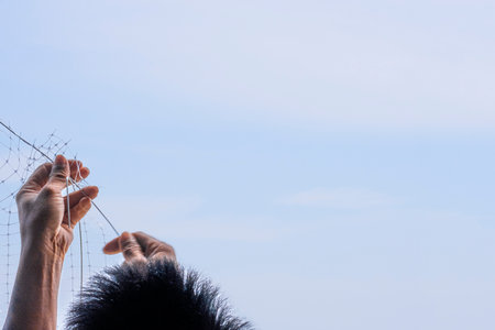 technician worker man install plastic net for protect pigeon bird in balcony apartment. Professional service man setup netting birds for clean and hygiene. Isolated on blue sky backgroundの写真素材