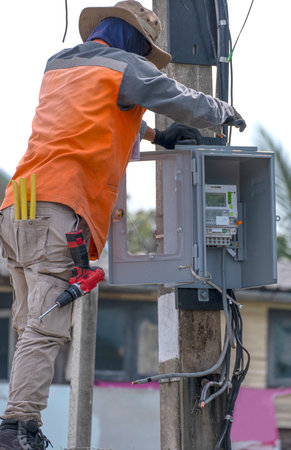 electrician man install Electronic digital energy meter and electric wire at high electric pole