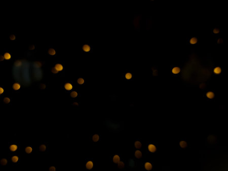 abstract bokeh light orange and yellow glowing flare pattern black background in festival christmas