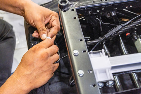 A skilled technician assembling and checking the electrical system and internal mechanism of an automatic electric sofa chair.の写真素材