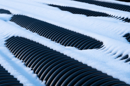 Black plastic Corrugated Drain Pipes covered by the Snow.の写真素材