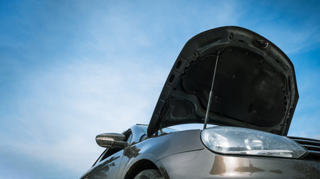 Low-angle view of open car hood against blue sky background with copy space.の写真素材