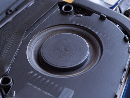Close-up view of a spinning laptop cooler with dust particles around.