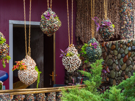 Colorful hanging planters filled with pebbles and vibrant plants create a lively display at a beautifully decorated outdoor space. The artistic design adds charm to the area.の写真素材