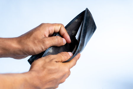 Close-up of hands holding an open empty wallet, symbolizing financial hardship, budgeting issues, poverty, or economic struggle. Ideal for finance-related themes.の写真素材