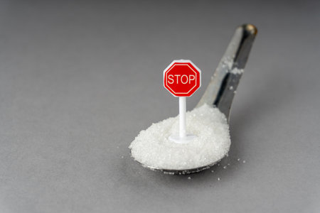 A symbolic photo showing a red stop sign embedded in white sugar on a spoonの写真素材