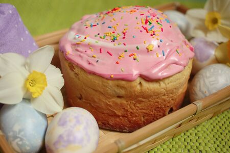 Easter cake and eggs with daffodils on a green background