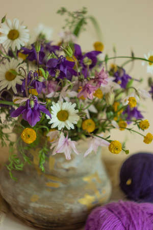 Still life of colorful flowers and knitting yarn, rustic style
