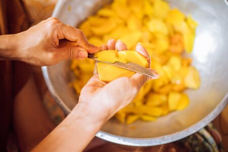 A woman's hand peeling mangoesの写真素材