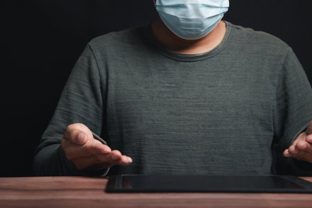 A young man's hand touched on a tablet, modern technology concept, empty space for text, studio photo on a black background.の写真素材