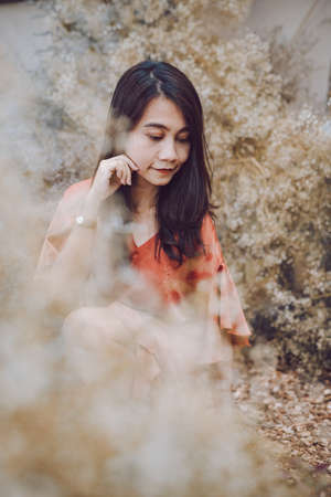 A beautiful woman dressed in a brown dress in the middle of a forest rich in colorful flowers,...