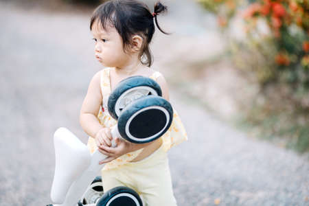 An Asian girl is enjoying her little bike during the day.の写真素材