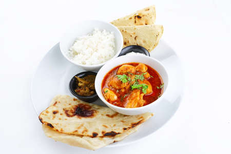 Indian chicken curry with rice and naan bread on white background.