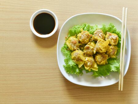 Dumpling arranged on a plate with a sauce for dunking on a wooden table. Shu Mai served on a plate on a wooden background.の写真素材