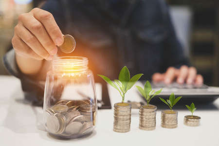 Hand holding coins in a jar to save money.Savings money concept.の写真素材