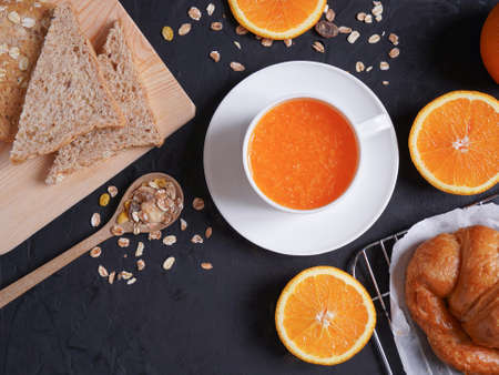 Breakfast with fresh orange juice, bread and croissants placed on black table background.の写真素材