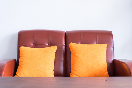 red leather sofa with orange pillowsの写真素材