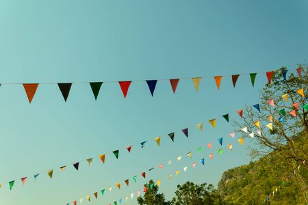 colorful festive bunting flags against a blue sky background in retro and vintage tone