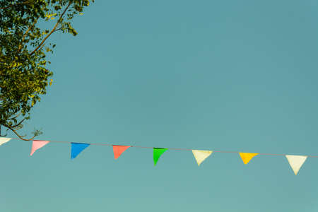 colorful festive bunting flags against a blue sky background in retro and vintage toneの写真素材