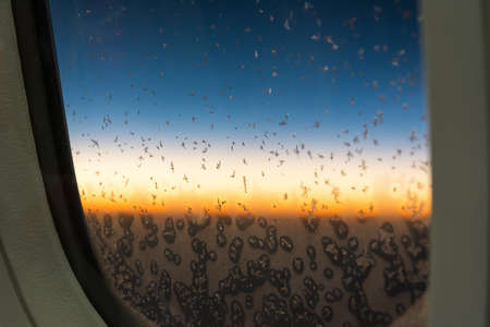 snow on plane window with sun rise backgroundの写真素材