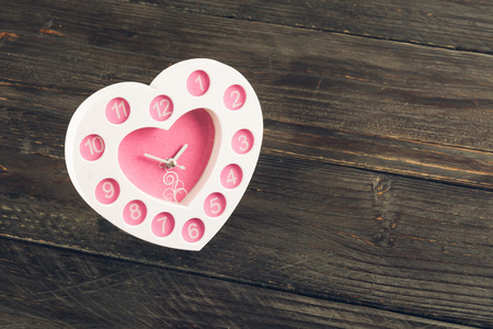 heart shape clock on wood - soft focus with vintage film filterの写真素材