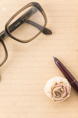 old paper with pen, glasses and rose on white backgroundの写真素材