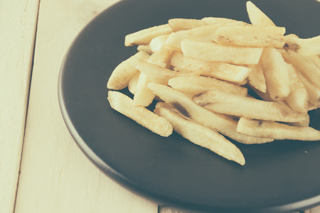 french fries on wood background - soft focus with vintage film filter
