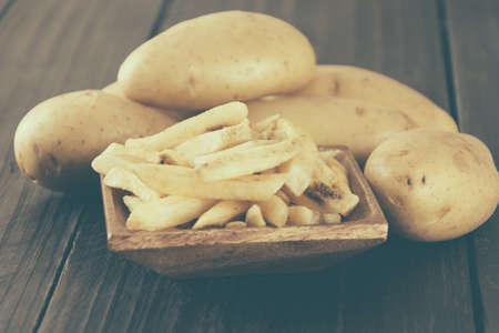 french fries on wood background - soft focus with vintage film filter