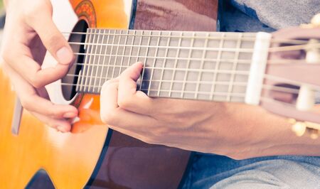 hand playing on acoustic guitar - soft focus with vintage filter