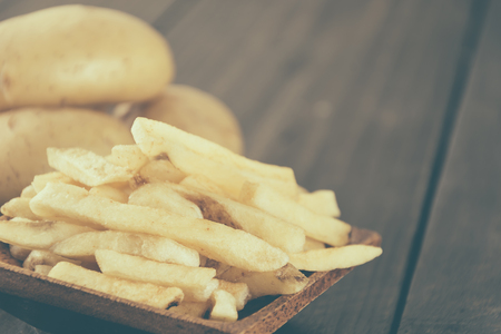 french fries on wood background - soft focus with vintage film filter