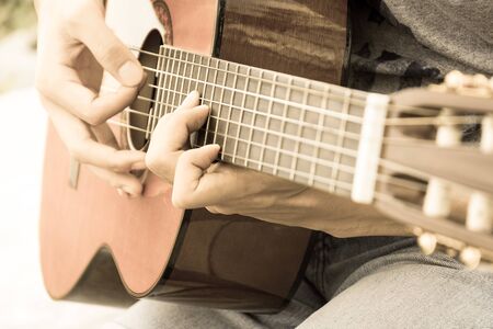 hand playing on acoustic guitar - soft focus with vintage filter