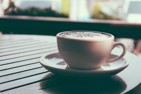 a cup of coffee on wood - soft focud with film filterの写真素材
