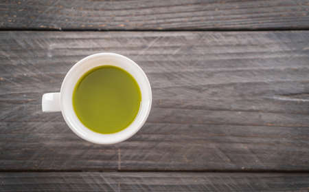 hot matcha on wood background - soft focus with vintage film filter