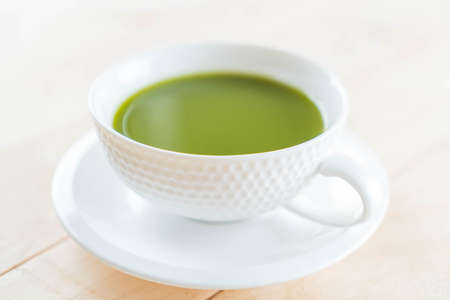 hot matcha on wood background - soft focus with vintage film filter