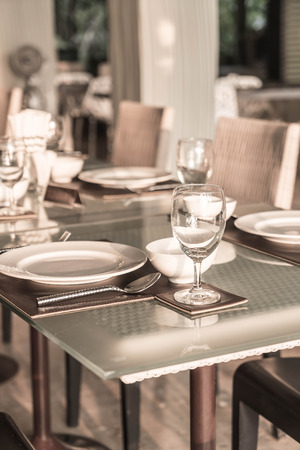 Selective focus point on wine glass with table setting for dinning in hotel restaurant - Vintage Light Filterの写真素材