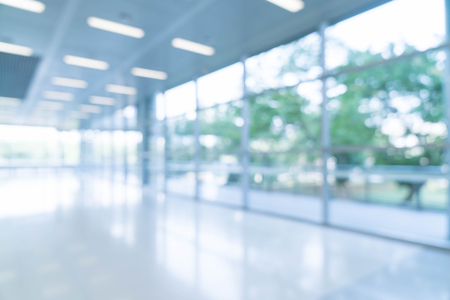 Blurred abstract background interior view looking out toward to empty office lobby and entrance doors and glass curtain wall with frame - blue white balance processing styleの写真素材